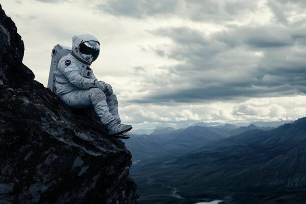 Astronaut auf felsigem Gipfel in Wolken