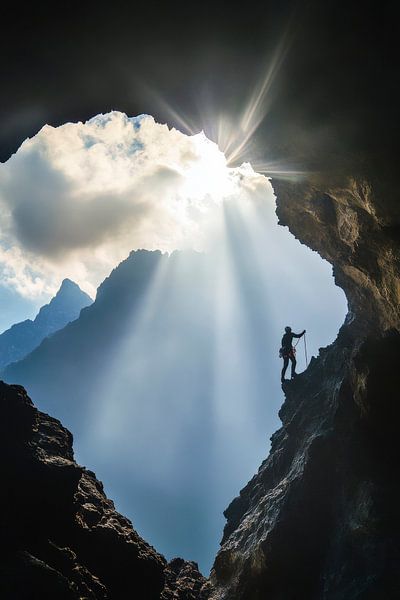 Bergsteiger im Höhleneingang mit Licht