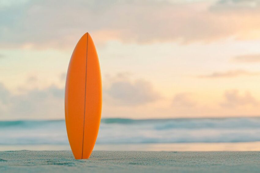 Orange Surfbrett am Strand bei Sonnenuntergang